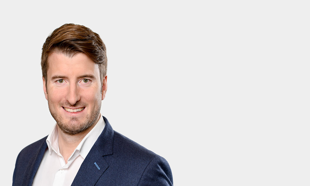 Martin Groicher, Senior Consultant Portraetfoto von Martin Groicher vor grauem Hintergrund