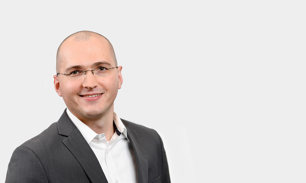 Sebastian Grundstein, Senior Consultant Portraetfoto von Sebastian Grundstein vor grauem Hintergrund