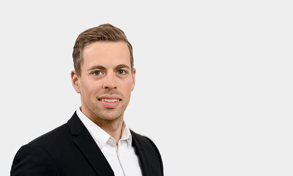Julian Hoeschle, Consultant Portraetfoto von Julian Hoeschle vor grauem Hintergrund