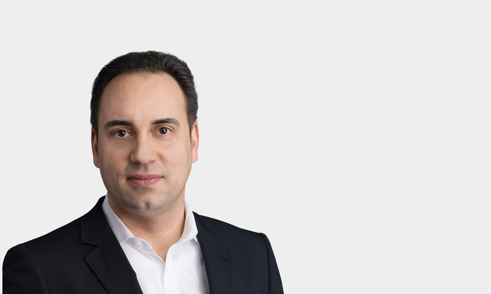 Tayfun Kaymakci, Leiter ROI Learning Campus Portraetfoto von Tayfun Kaymakci vor grauem Hintergrund