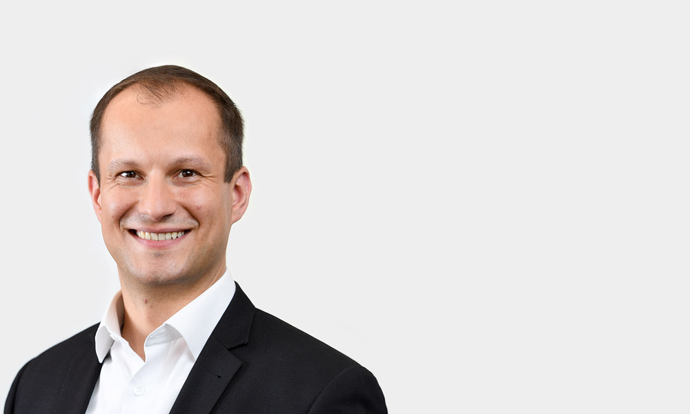 Christian Koenig, Senior Consultant Portraetfoto von Christian Koenig vor grauem Hintergrund