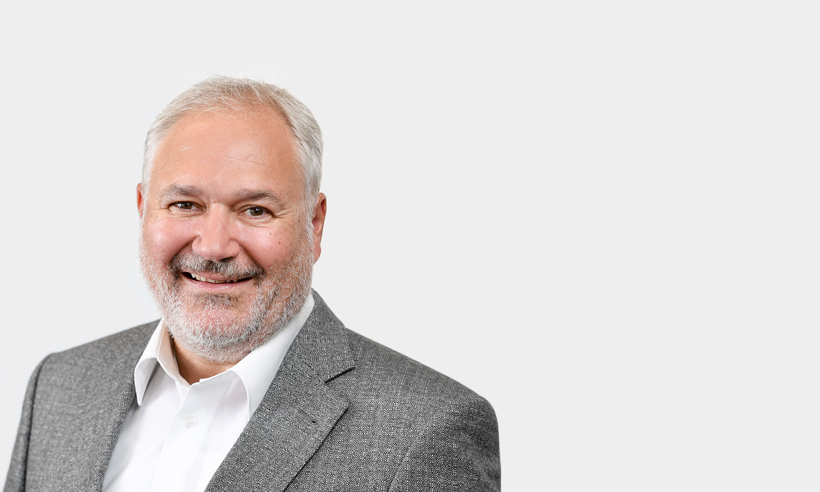 Uwe Koschel Senior Expert Portraetfoto von Uwe Koschel vor grauem Hintergrund